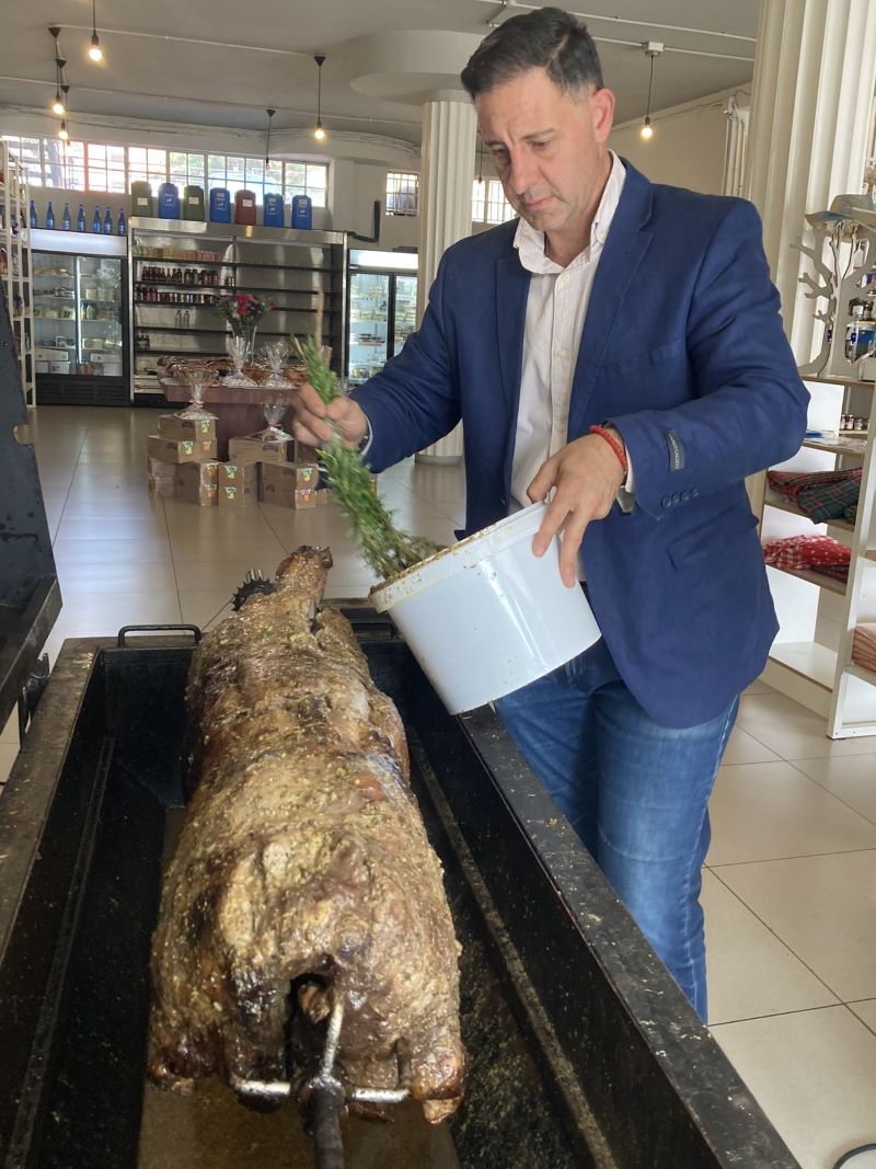 Basting the lamb on the spit with rosemary