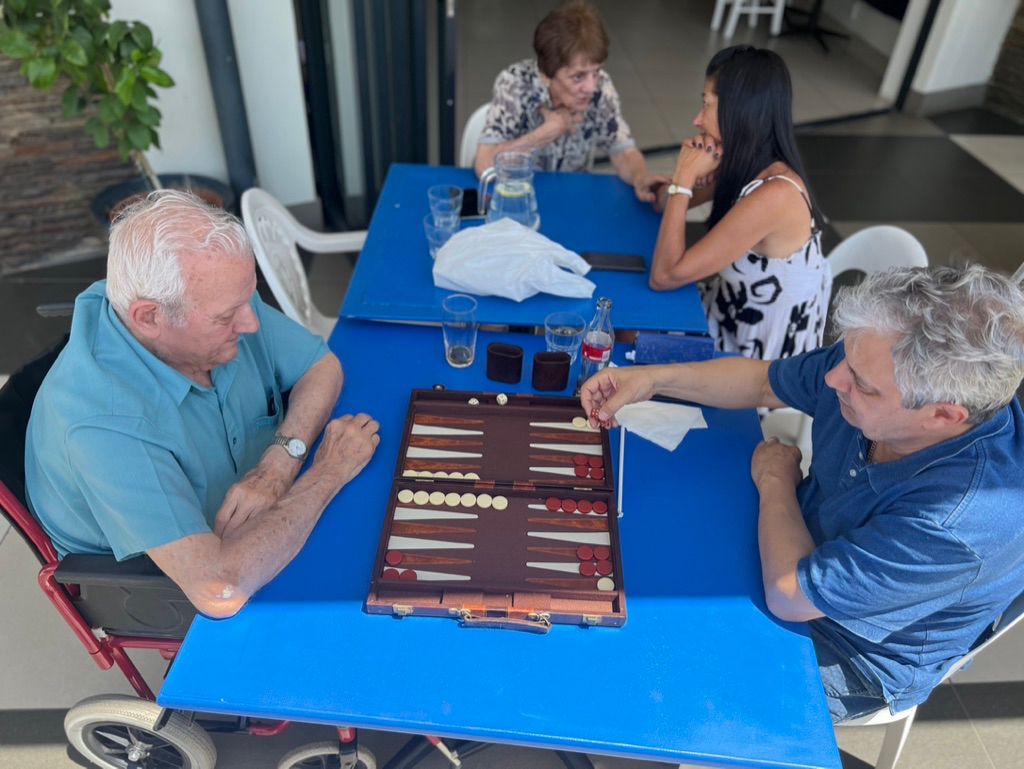 Friends playing tavli around the blue tables