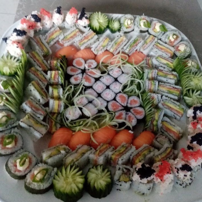 Sharing platter of rainbow rolls, maki and cucumber garnishes