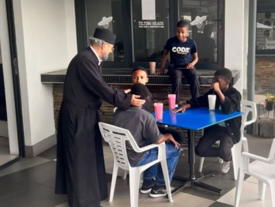 Priest greeting young guests outside the cafe