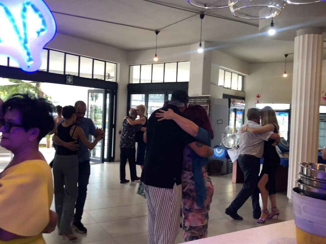 Couples dancing under the neon sign at Meraki Deli Cafe